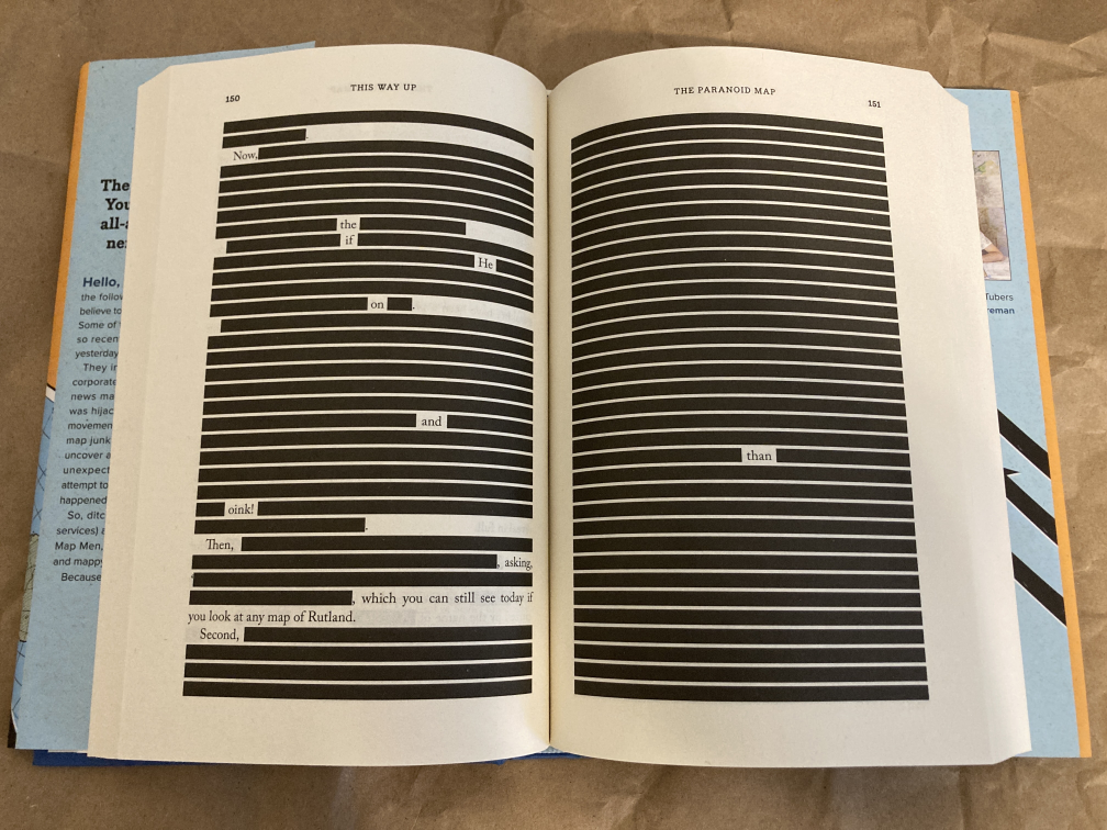 An image of the book This Way Up, with the pages opened to a page that is almost entirely censored. On the second page, only 1 word is visable through black censor bars.